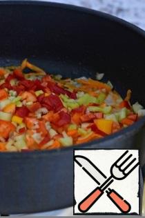 Then add the chopped bell pepper and chopped tomatoes to the carrots and onions. Simmer the vegetables under the lid for ten minutes.
