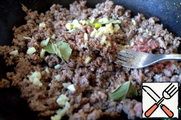 When the minced meat is caught on the fire, add the garlic, Bay leaf and spices.