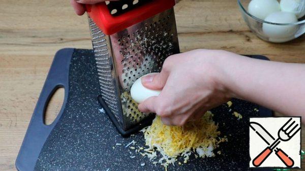 Boil, cool and peel the eggs. Grate them on a fine grater.