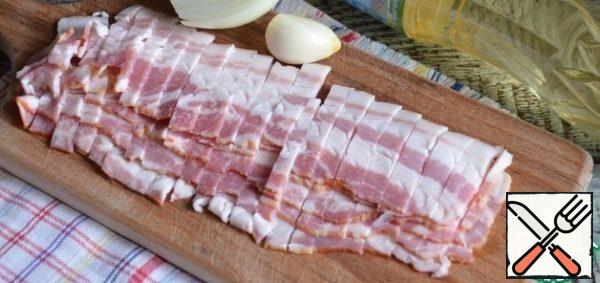 Cut the bacon into thin strips and fry in vegetable oil, set aside some of it for serving. Onion and garlic cut, fry with bacon.