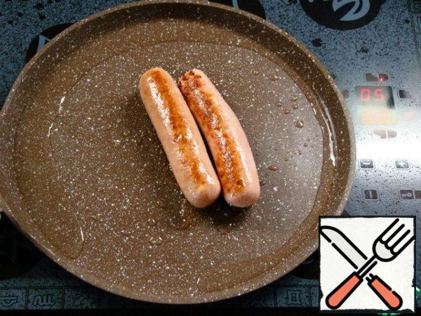 Pour 1 tablespoon of oil into a preheated frying pan. Fry the sausages on all sides until Golden brown. And then reduce the heat to medium.