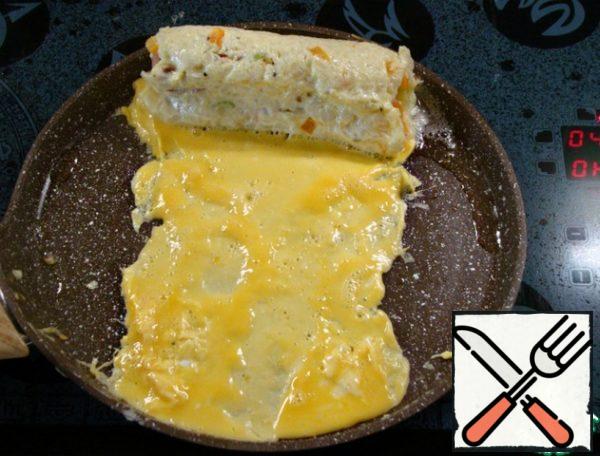 Then move the roll to the edge and carefully pour 1/4 of the egg omelet, trying to form the edges and width of the omelet, the width of the rice roll. Add vegetable oil if necessary.