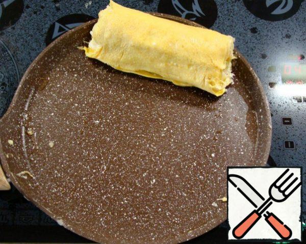 As soon as the omelet grabs, carefully, again using two spatulas, roll up the roll and move it to the edge of the pan.
