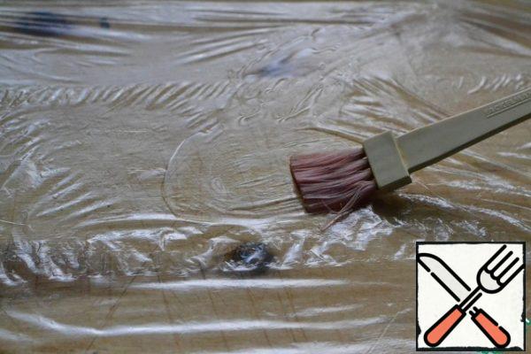 Cover the cutting Board with cling film, which is liberally greased with sunflower oil.