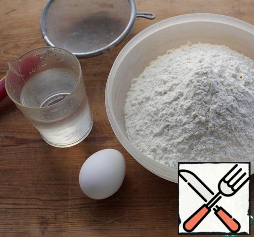 First of all, prepare the dough. In water, dissolve a teaspoon of salt, beat in the egg, stir.
Sift the flour into a Cup, make a recess in it, pour in the liquid, knead the dough.