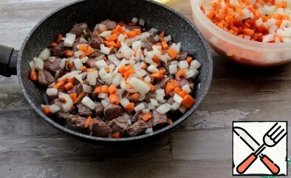 Fry the meat, onions, and carrots in the preheated oil for 20 minutes.
