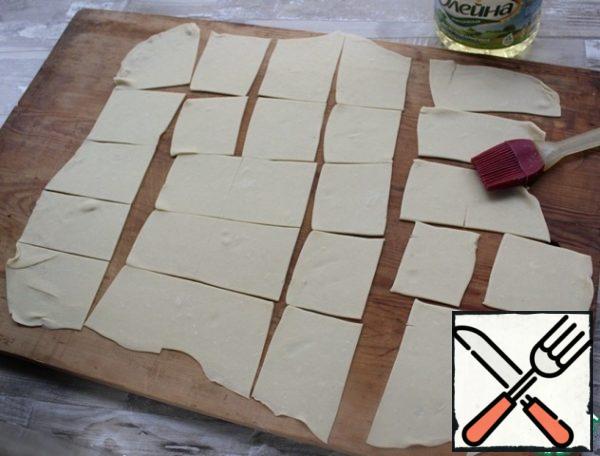 The finished dough is thinly rolled out, cut into small rectangles, grease with vegetable oil.