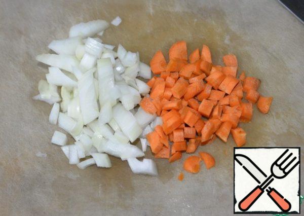 Onions and carrots are cleaned and cut into cubes.