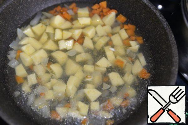 We take a frying pan with high sides or a saucepan, heat it, pour oil. Fry the vegetables until soft over medium heat, put the diced potatoes, fill with fish broth.