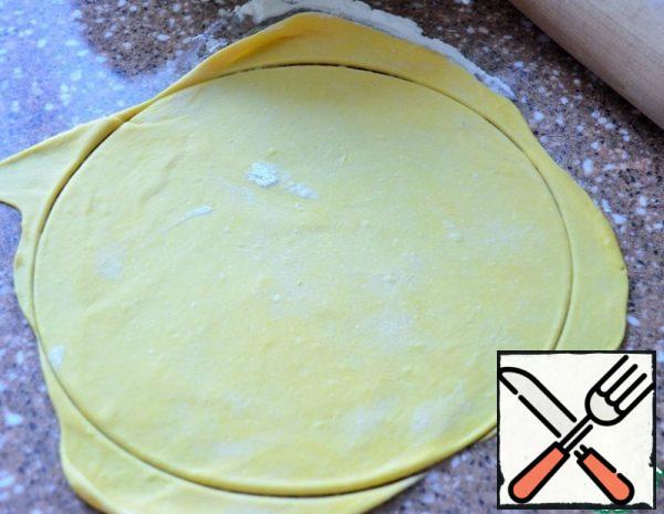 Divide the dough into pieces of 80-85 g.. Roll up in koloboks, cover with cling film. Roll out the bun on a work place dusted with flour, cut out a circle, 24 cm..