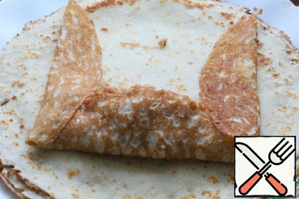 Spread the filling on the pancake, bend it from the sides and bottom, roll it into a roll.