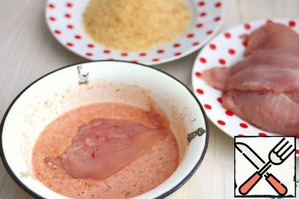 Place the prepared chicken breast fillet in the prepared egg batter, then sprinkle well with breadcrumbs and place in a preheated frying pan with oil.