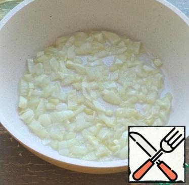 For the filling, peel the onion, wash it, and cut it into cubes. Pour the vegetable oil into the pan and fry the onion for a minute.