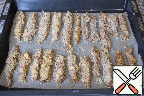 Each piece of chicken fillet is dipped first in an egg, and then rolled in breadcrumbs. I put all the strips of chicken fillet on a baking sheet covered with parchment for baking.