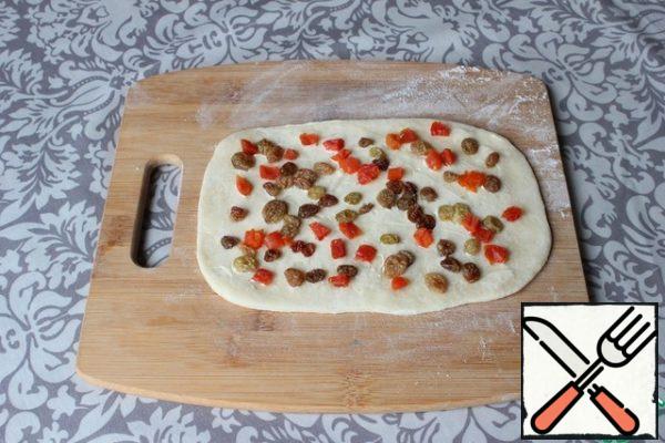 "Coming up" dough obmenu. I divide it into 6 equal parts. Each piece is rolled into a rectangular layer (about 15 by 20 cm).
I lubricate the rectangle with butter.
Spread raisins and dried apricots evenly on the dough with butter. I press them a little into the dough.