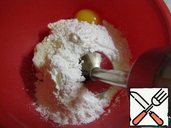Let's do the cheesecake cream. Take the container and put the cottage cheese in it. I advise you to take cottage cheese, which is more uniform, not grains. By fat content, take it to your taste. I tried with cottage cheese of different fat content, the difference in taste did not feel.
Add sour cream, powdered sugar, one egg, and vanilla to the curd. If you will use small eggs (C-1,2), then take two. I draw Your attention that I am using vanillin-intensive. From the usual vanilla, it has a more creamy taste. If you do not neglect such things, then feel free to take it. Add a little vanilla: a small pinch or on the tip of a knife. We punch all the ingredients with an immersion blender until smooth. It is important at this stage to break through to smoothness, so that there are no grains.
