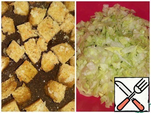 Garlic pass through the press. Slice the bread, cover with garlic and fry in olive oil.
Tear or chop the lettuce leaves.