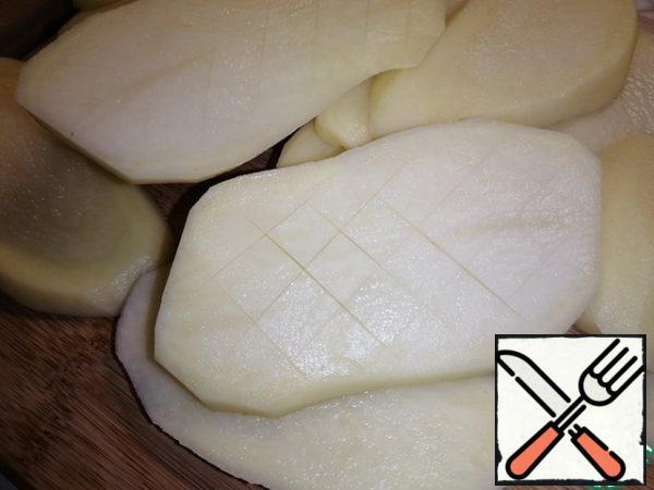 Carefully make oblique incisions so as not to cut the potatoes to the end and get squares.