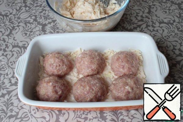 I lubricate the baking dish with sunflower oil. I put half of the grated potatoes on the bottom. I spread the balls of cutlets on top.