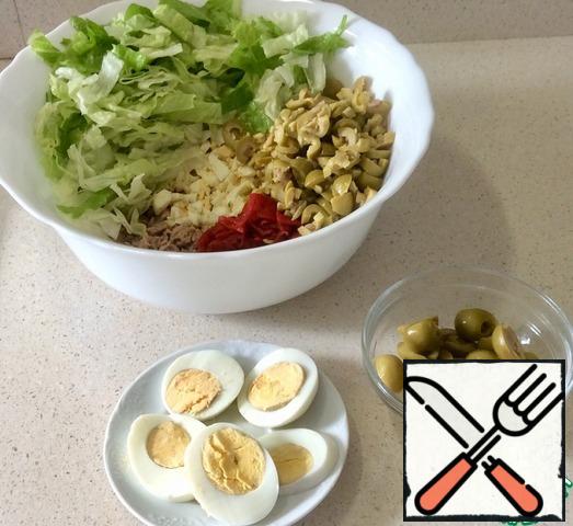 Carefully remove the tuna from the jars, squeeze out the excess liquid and chop it with a fork. 3 eggs finely crumble, 1 cut into rings for decoration. Finely chop the Lecho pepper. 10-12 olives cut in half for decoration, the rest finely, like pepper. Cut the lettuce leaf into short strips.