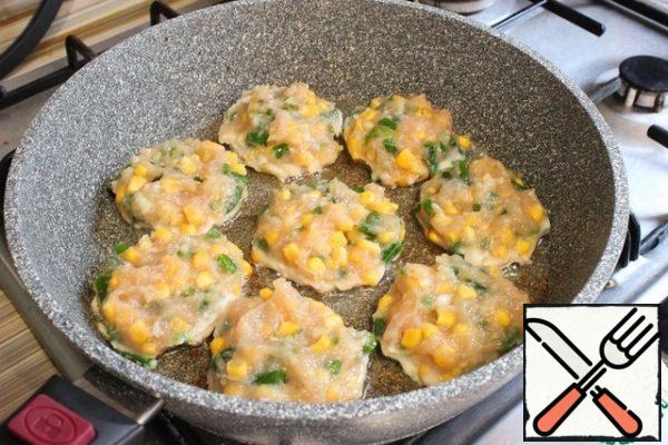 I put the pan on the fire and warm it up. I pour in sunflower oil. Spoon the chicken mass into the pan and form flat pancakes.