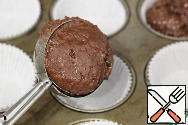 Spread the dough into muffin molds. It is convenient to do this with an ice cream spoon.