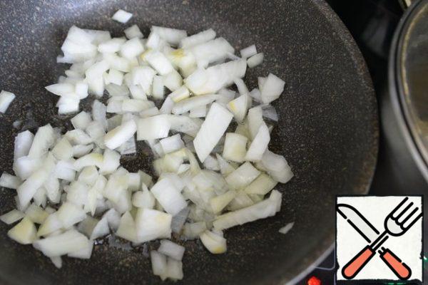 Pour vegetable oil into the pan. Cut the onion into cubes and lightly fry over medium heat in oil.