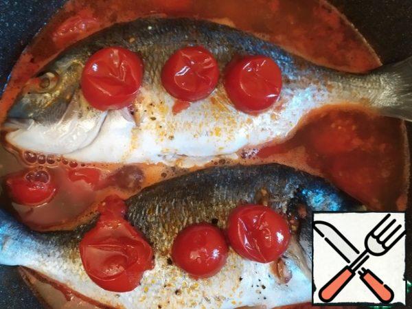 Top with a few tomatoes. Turn down the heat and cover. Cook for about 20 minutes. Periodically opening the lid and pouring the fish with the sauce in which it is prepared.