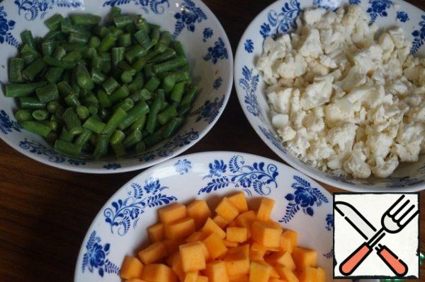 Prepare the vegetables. Peel the pumpkin and cut it into small cubes. We will sort the cauliflower into inflorescences and also cut it into small cubes. Beans can be taken frozen or fresh. Cut the bean pods into 2-3 pieces.