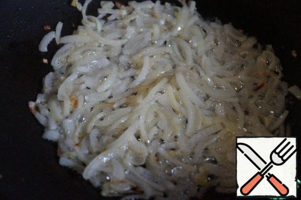 Pour vegetable oil into a preheated frying pan. Peel one onion and cut it into half rings. Fry the onion in vegetable oil until Golden.