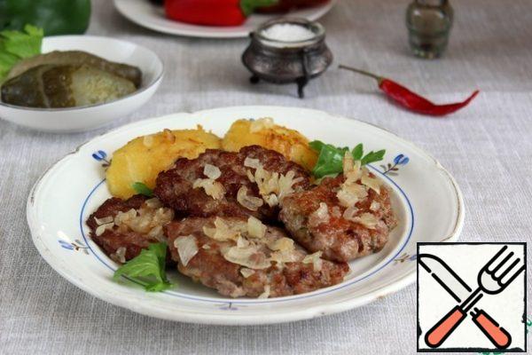 Ready cutlets put on a plate, top with fried onions.
