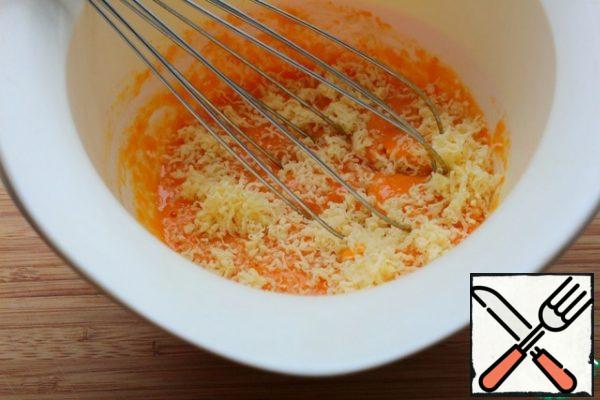 Grate 50 gr of cheese on a fine grater, cut the rest into small cubes.
Put the pumpkin puree and eggs in a bowl and mix.
Add the grated cheese and mix.
