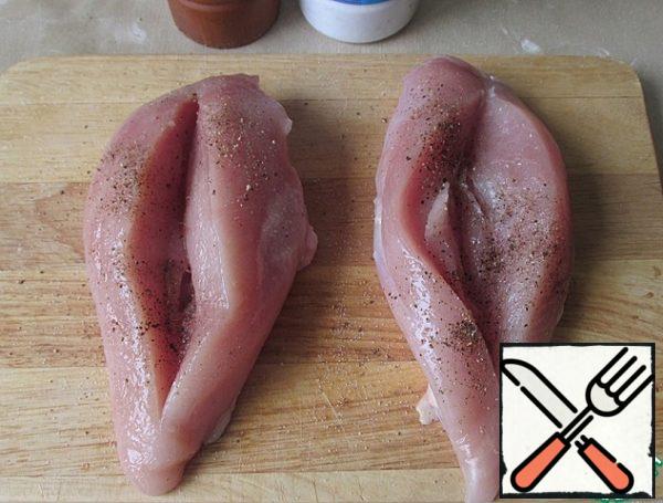 We need two thick chicken breast fillets.
Each fillet is cut through the pocket, taking care not to cut right through him. Sprinkle with salt and pepper on top and in the slits.