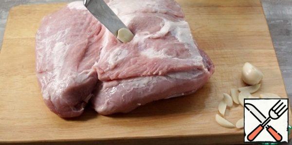Cut the garlic into pieces. We mercilessly stick a knife into the flesh of pork, make a puncture and insert slices of garlic along its blade. Garlic can be taken from the heart.