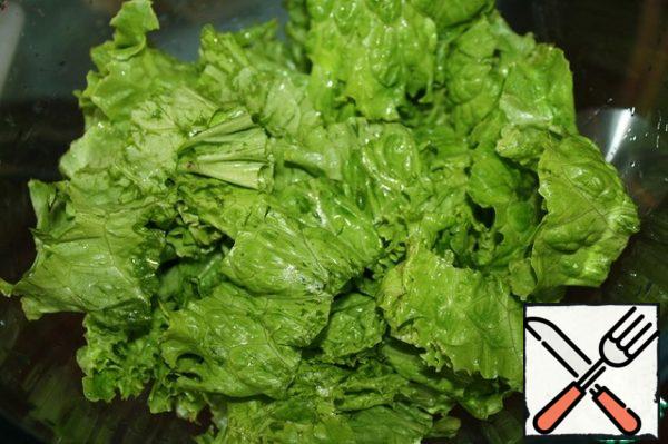 Washed and pre-soaked in cold water lettuce leaves randomly break, put on a dish.