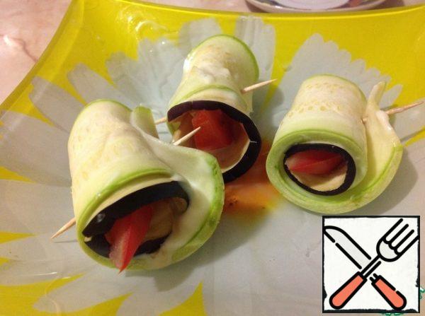 We take a quarter of a tomato (instead of a tomato, it can be an Apple or a pear, also very tasty and unusual) and wrap it with eggplant, and this is still wrapped with zucchini.
Fix it with a toothpick (s) and continue doing so until our vegetables run out.