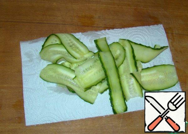 We send it to a frying pan heated with vegetable oil and fry on both sides until Golden brown for 2-3 minutes. Cut the cucumber with a vegetable peeler into thin strips. Spread on a paper towel to remove excess liquid.