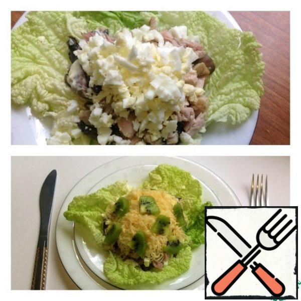 The next layer is a boiled egg, finely chopped, and a layer of mayonnaise. And the picture is completed with finely grated cheese and peeled kiwi, thinly sliced into triangles.