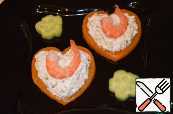 Boil the prawns in salted water for 3-5 minutes and let cool. Clear. Drizzle with vermouth and vegetable oil. Arrange the pumpkin hearts on a platter, put a spoonful of the cheese and cucumber mixture on each, and put the shrimp on the mixture.