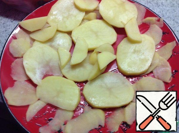 Wash and peel the potatoes. Cut into pieces and put on a plate greased with vegetable oil.