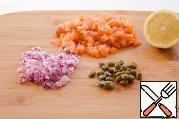 Finely chop fresh or lightly salted salmon with a knife. Chop the onion very finely. Cut the capers and add them to the onions and fish. Add salt and pepper to taste. Drizzle with lemon juice.