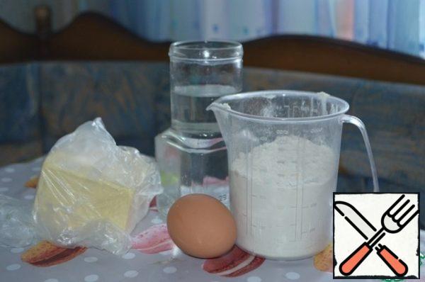 Chop the butter with a knife, separate the yolk from the egg, sift the flour with salt. Knead the dough by hand, adding cold water.