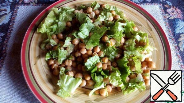 Now you can collect the salad. Place the coarsely chopped lettuce leaves on a serving plate and top with the chickpeas. Mix vegetable oil, mustard, vinegar, salt and pepper for dressing. Pour part of the dressing over the salad and chickpeas and mix everything lightly.