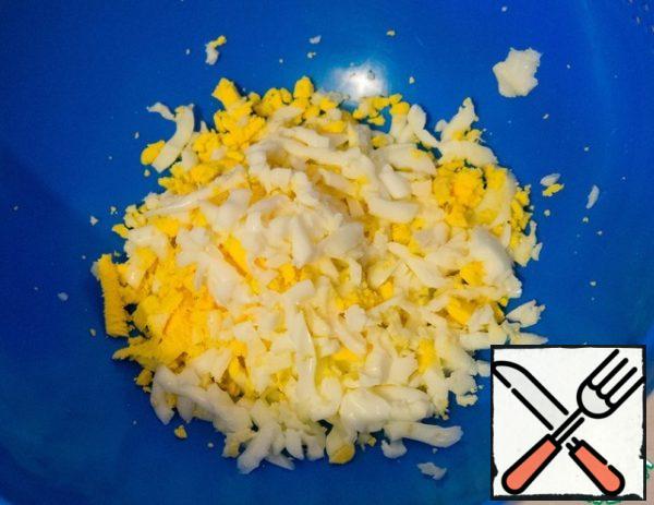 Grate the boiled eggs on a coarse grater.