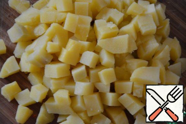 Boil the potatoes in water (or cook in a steamer) in the peel until tender. Clear. Cut into small cubes.