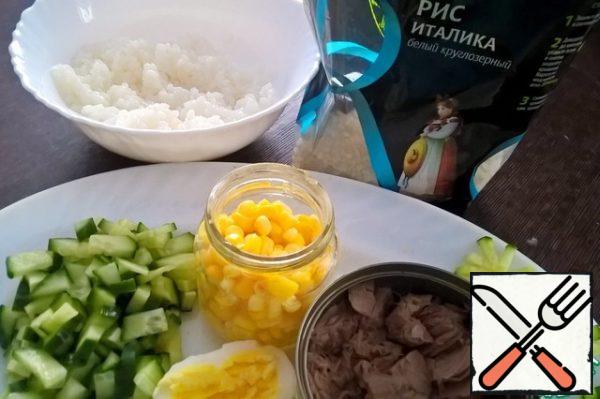 Prepare the ingredients.
Boil the rice
Boil the egg and finely chop it
With canned food drain the liquid and mash with a fork
Finely chop the cucumber
Drain the liquid from the corn
