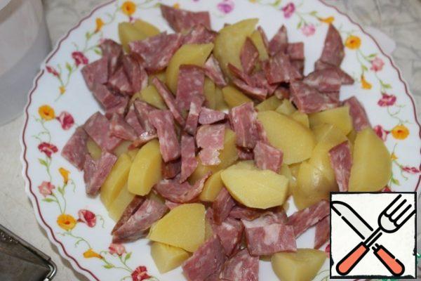 Cut the sausage into thick strips. Spread on a dish with potatoes.