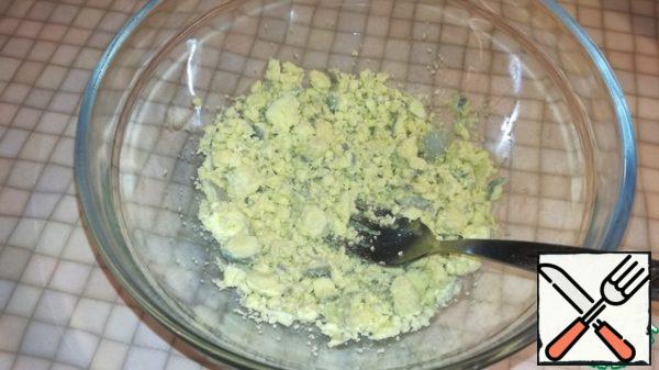 Peel the eggs and cut them into halves. Carefully remove the yolks and grind in a deep bowl.