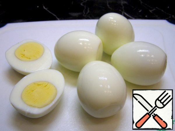 Cut the hard-boiled eggs in half and remove the yolks.