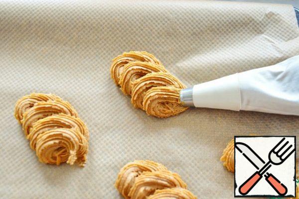 Fold the dough into a pastry bag. Put the cookies in any shape. It is better to put on parchment to make it easier to remove.

From experience, I will say that the dough is quite difficult to put out of the pastry bag. You can just put it on a baking sheet with two teaspoons.